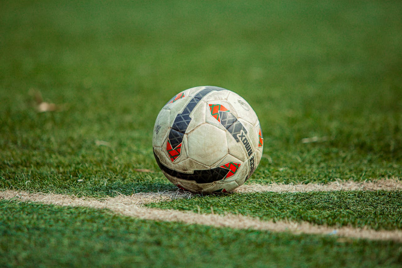 A close-up of a soccer ball on a green field with white lines, perfect for sports and recreation themes.