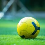 Close-up of a yellow soccer ball on a green field, perfect for sports and recreation themes.