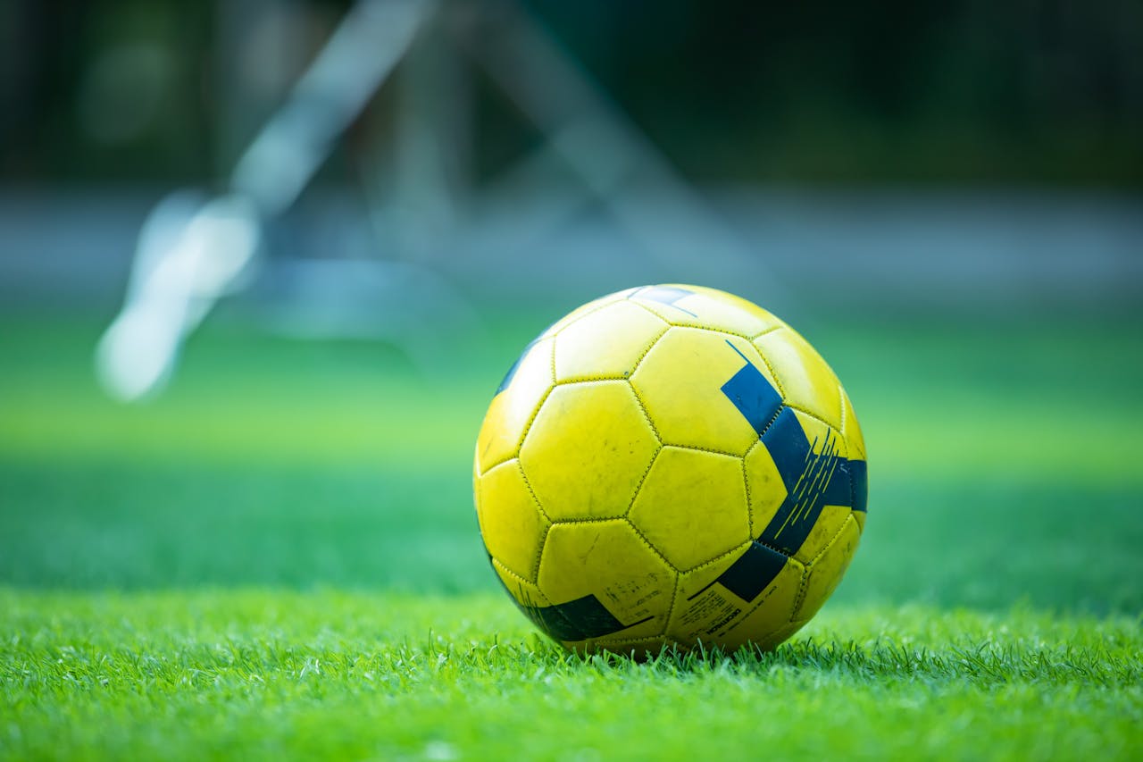 Close-up of a yellow soccer ball on a green field, perfect for sports and recreation themes.